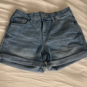 Blå jeansshorts - Snygga blå jeansshorts med uppvikta ben. Har använts en gång och är i storlek XS. De är både high o mid waisted