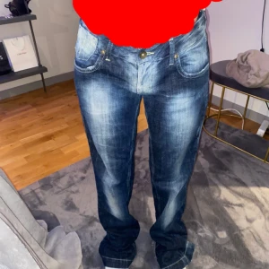 Blå jeans med dragkedjedetaljer - Snygga blå jeans med coola dragkedjedetaljer på bakfickorna. De har en klassisk femficksdesign och en lätt tvättad look som ger en avslappnad stil. Perfekta för en casual outfit. Finns inte att köpa längre då de är från år 2008 från Fornarina