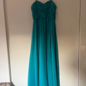 Turkos långklänning från Gina Tricot - Säljer en vacker turkos långklänning från Gina Tricot. Klänningen har smala axelband och en draperad överdel som ger en elegant look. Perfekt för speciella tillfällen. 💙