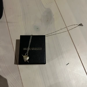 Halsband med hjärthänge från Maria Nilsdotter - Jättefint halsband från Maria Nilsdotter med gulligt hjärta. Relativt använt skick. ⭐️nypris 3695kr