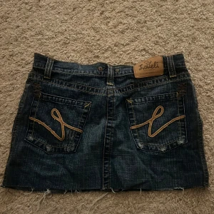 Jeanskjol från loveli - Snygg jeanskjol från loveli med slitna detaljer och dekorativa sömmar på bakfickorna. 