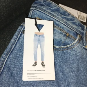 Blå jeansbyxor med croppad slim passform - Snygga blå jeans med en avslappnad topp och smal avsmalnande ben. De är croppade precis ovanför ankeln, vilket ger en modern look. Perfekta för en stilren vardagsoutfit.