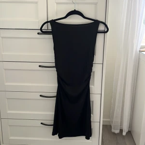 Svart klänning från H&M Divided - Snygg svart klänning från H&M Divided i en enkel  design. Klänningen är ärmlös och har en tight passform. 