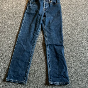 Levis 501 jeans - Klassiska Levis 501 jeans i blå denim. Dessa jeans har en rak passform och är högmidjade med den ikoniska Levis-lappen på baksidan. Perfekta för en tidlös stil.