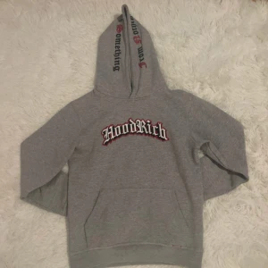 Grå hoodie från Hoodrich - Säljer en grå hoodie från Hoodrich med texten 'Hoodrich' på bröstet och 'From Nothing To Something' på huvan. Hoodien har en klassisk passform med känguruficka framtill. Perfekt för en avslappnad stil. Som är i storlek XL i barn så ungefär s/xs i herr 