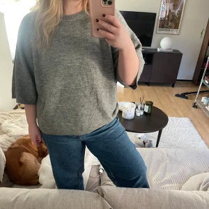 Grå tröja med trekvartsärm - Mysig grå tröja med trekvartsärm, perfekt för en avslappnad stil. Tröjan har en enkel design och är lätt att matcha med olika outfits.