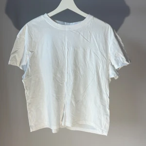 Vit t-shirt från H&M - En klassisk vit t-shirt från H&M i bomull. Perfekt basplagg med rund hals och korta ärmar. Enkel och stilren design som passar till det mesta.