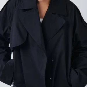 Svart trenchcoat - Snygg svart trenchcoat med klassisk design och bred krage. Perfekt för en stilren look. Jackan har en lös passform och långa ärmar. Prislapp är kvar. 