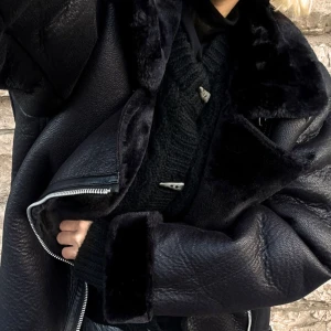 Svart skinnjacka med pälsdetaljer  - Klassiskt pilotjacka med bondat material. Använd fåtal ggr, säljer för 300kr. Skulle säga den har en oversize passform 