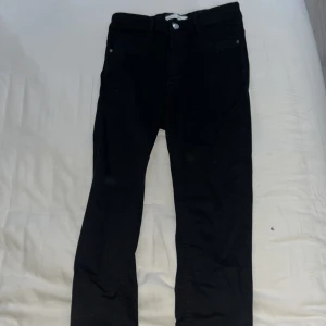 Svarta jeansbyxor - Snygga svarta jeansbyxor med en klassisk design. De har en hög midja och raka ben, vilket ger en tidlös look. Perfekta för en stilren outfit.