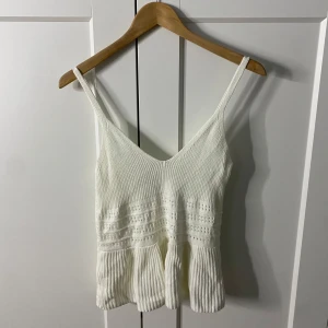 Vit sommartopp  - Säljer en vit stickad linnetopp från Primark med smala axelband och ett fint hålmönster. Toppen har en lätt utsvängd nederdel. Toppen passar perfekt inför sommaren!