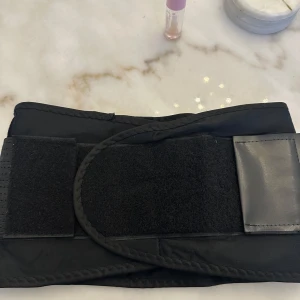 Svart midjebälte med kardborre - Säljer ett svart midjebälte med justerbar kardborreknäppning. Bältet har en elastisk design med perforerade detaljer för extra andningsförmåga. Perfekt för att ge stöd och form åt midjan. Väldigt skönt att använda vid ryggproblem! Säljes pga fel storlek. Storlek L, längd 89cm bredd 19cm. Mycket justerbart inåt pga rejäl kardborre. Använt men i bra skick. Köpt på Amazon. 