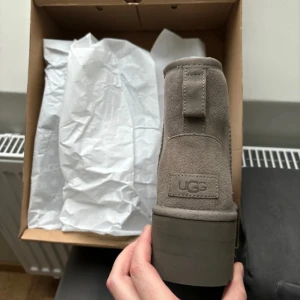 Grå boots från UGG - Säljer ett par grå boots från UGG i mocka med en mjuk och varm insida. Skorna har en robust sula och är perfekta för kyligare väder. De är i storlek dam 38 och tillverkade i Vietnam.
