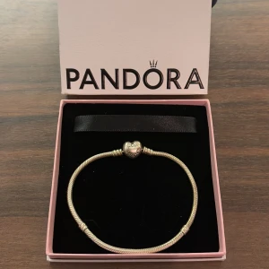 Berlockarmband från Pandora - Berlockarmband från Pandora i silver med ett hjärtformat lås. 💗Perfekt för att bära ensam eller med berlocker. Kommer i original förpackning.🥰 Storlek 21. Köpte för 800kr nästan aldrig använt så säljer för 600kr