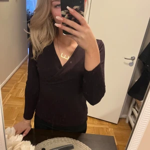 Svart omlottopp - Snygg brun omlottopp med långärmad design. Perfekt för en stilren look.