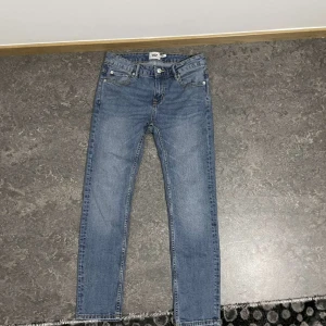 Blå jeansbyxor - Snygga blå jeansbyxor med klassisk femficksdesign och dragkedja. Perfekta för en avslappnad stil. De har en straight passform och är tillverkade i slitstarkt denim.