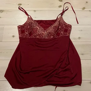 Rött linne med spets - Snygg vinröd topp med justerbara axelband och vacker spetsdetalj över bysten. Spets delen är genomskinlig och resten är i silkesliknande material💕💕