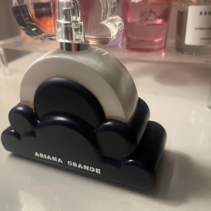 Ariana Grande Cloud 2.0 Parfym - Ariana Grande Cloud 2.0 intense är en elegant parfym med en unik flaska formad som ett moln. Flaskan är vit med en mörkblå bas och har en transparent, hjärtformad topp. Den kommer i en stilren blå förpackning. Perfekt för den som älskar en söt och drömsk doft. Har kvar kartongen den kom i. Fick den i julklapp och är inte min typ av doft. Har sprutat några gånger för att försöka gilla den men tyvärr faller den inte i min smak. Nypris 800kr