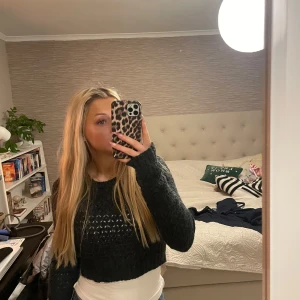 Mörkgrå stickad tröja - Säljer en mysig mörkgrå stickad tröja med ett snyggt mönster. Tröjan är croppad och har långa ärmar, perfekt för kyligare dagar. Den har en ribbad kant vid ärmslut och nederkant. Perfekt att ha över linne. Storlek 38 men passar även 36💘💘💘