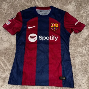 Fc Barcelona hemma ställ 23/24  - Tja! Säljer denna officiella FC Barcelona fotbollströja från Nike med Lamine Yamal och nummer 27 på ryggen❗️| Skick: 9/10! Har bara använts ett få tal gånger! | Storlek: S passar också XS! | Ny pris ca 2200kr 💵| Färg: Röd och blå ❤️💙| Tillbehör: Tyvärr följer inga tillbehör med denna varan 🙁| Fraktar: Spårbart genom PostNord och Instabox 📦| Hör av er för mer information! | Allt gött! 😉👊
