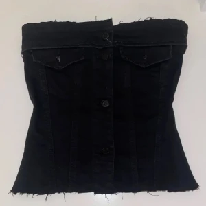 Svart tubtopp i jeans - Snygg svart tubtopp i jeansmaterial med knappar framtill. Toppen har en rå kant upptill och nedtill för en trendig look. Perfekt för en cool och avslappnad stil. Sydd sjölv 