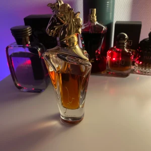 Lattafa Maahir gold - Elegant parfymflaska med ett unikt hästhuvud i guld som lock. Flaskan har en klar design som visar den gyllene vätskan inuti. Perfekt för den som vill ha en lyxig och iögonfallande detalj på parfymhyllan. Ca 90ml kvar