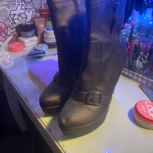 Bruna stövlar med spänne - Snygga bruna stövlar med dragkedja och dekorativt spänne. Perfekta för höst och vinter, dessa stövlar är både stiliga och praktiska.