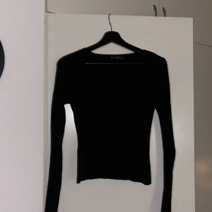 Svart ribbad tröja från Lefon - Snygg svart ribbad tröja från Lefon i storlek S. Tröjan har en v-ringad design och långa ärmar, perfekt för en stilren look. Passar bra till både jeans och kjol.