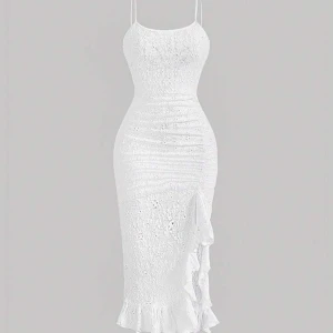 Vit spetsklänning med volangdetaljer - Helt ny, Elegant vit klänning i spets med smala axelband och volangdetaljer längs sidan. Den har en tight passform som framhäver figuren och en vacker volangkant vid fållen. Perfekt för sommarens festligheter.