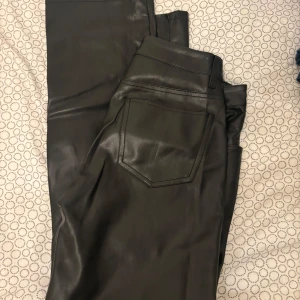 Svarta skinnbyxor från Bik Bok - Snygga svarta skinnbyxor från Bik Bok med klassisk femficksdesign och knappgylf. Perfekta för en stilren look. Köpta för 599kr