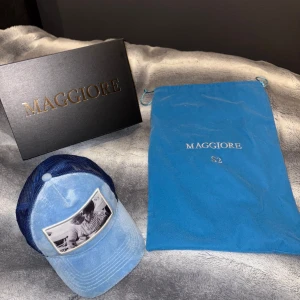Blå keps från Maggiore(limited edition) - Snygg blå keps från Maggiore med ett unikt fototryck på framsidan. Kepsen har en klassisk design med justerbar passform och nätmaterial på baksidan för extra ventilation. Perfekt för en avslappnad stil. Kepsen är Limited edition och ör c2. Hör av er vid minsta fundering.mvh Charlie 🤝