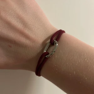 Vinrött armband med silverdetalj - Snyggt vinrött armband med en stilren silverfärgad detalj. Man kan självklart sjustera passformen på armbandet med knutarna! Är öppen för frågor och prisförslag🤩 ALDRIG ANVÄNT!!