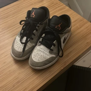Nike Air Jordan sneakers i grått och svart - Snygga Nike Air Jordan sneakers i grått och svart med svarta snören och orange detaljer. Perfekta för en sportig look. Skorna har en klassisk design med perforerade detaljer på tån och en ikonisk Nike-logga på sidan. Är i mocka och mockan har missfärgats lite. 
