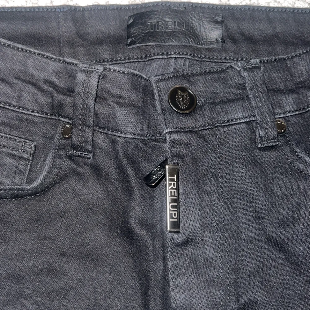 Unika svarta jeans från Trelupi med coola patchar och slitningar. Byxorna har en midwaist design och är dekorerade med en iögonfallande vargpatch samt flera andra detaljerade patchar. Perfekta för en edgy look.. Farkut & Housut.
