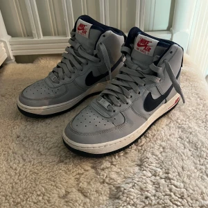 Grå Nike Air Force 1 sneakers - Tjena! Nu säljer jag mina snygga grå Nike Air Force 1 sneakers i den höga modellen. Storlek: 37,5 men passar mig med 38. Skick 9/10 knappt använda, ingen box då jag köpte dom utomlands och det ej fick plats att ta med boxen och skorna. Hör av dig vid minsta fundering/prisförslag. 🙂