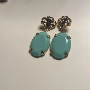 Turkosa örhängen med gulddetaljer - Eleganta örhängen med stora turkosa stenar i oval form, infattade i guldfärgade detaljer. Perfekta för att ge en färgklick till din outfit.