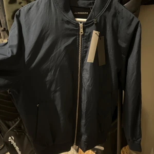 J.Lindeberg Bomberjacka  - Säljer en navy blå J.Lindeberg bomberjacka i storlek M. Aldrig använd med prislapp kvar