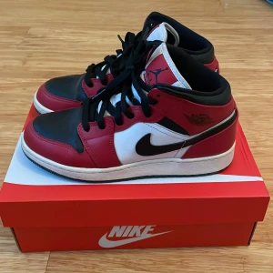 Nike Air Jordans i rött, svart och vitt - Snygga Nike Air Jordans i en klassisk färgkombination av rött, svart och vitt. Skorna har en ikonisk design med snörning och den välkända Nike-loggan på sidan. Perfekta för dig som vill ha en stilren och sportig look.