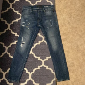 Blå jeans från Replay - Snygga blå jeans från Replay med slitna detaljer och en slim passform. De har en klassisk femficksdesign och dragkedja. Replay jeans modell Mickym. Skriv ifall det är någon fundering om passform osv! 