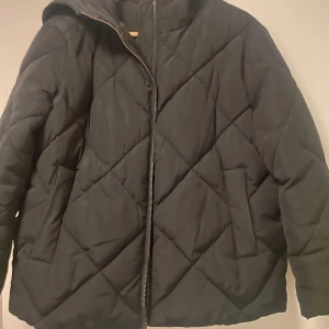 Svart quiltad jacka från ASOS - Säljer en svart quiltad jacka från ASOS i storlek M. Jackan har en dragkedja framtill och är perfekt för kyliga dagar. Den är både stilren och bekväm, idealisk för höst och vinter. Passar till alla outfits!