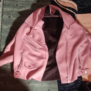 Rosa mockajacka med dragkedjor - Säljer en snygg rosa mockajacka i mycket bra skick. Jackan har flera dragkedjor och en cool bikerstil. Perfekt för höst och vår, och den är långärmad. Passar perfekt för en trendig look!