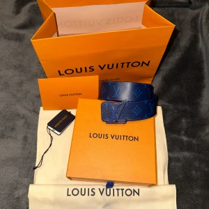 Reversible Louis Vuitton Bälte - Monogram Blå - 90cm - Säljer ett rare bälte från Louis Vuitton, i princip nytt skick, använt 2 gånger. Bältet har det klassiska LV-monogrammet och ett stilrent spänne med LV-loggan. Perfekt för att ge din outfit en lyxig touch. Kommer med allt og, originalförpackning, kvitto och påse. Köpt på LV butik i Spanien. 90cm