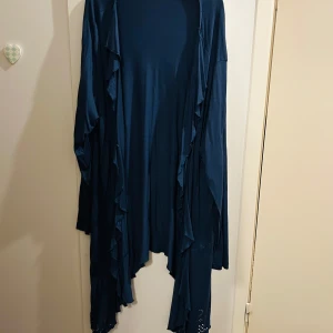 Mörkblå långärmad cardigan från Rainbow - Säljer en superfin mörkblå cardigan från Rainbow i storlek 48/50. Den har långa ärmar och en snygg volangdetalj längs kanterna. Perfekt för höst och vår! Materialet känns mjukt och skönt mot huden. Passar både till vardags och festliga tillfällen. 🌟