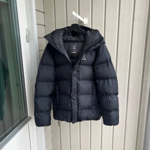Svart pufferjacka från Haglöfs - Säljer en svart pufferjacka från Haglöfs i herrstorlek M (passar L).  Perfekt inför vintern! Jackan köptes förra vintern och är nästan helt nyskick.  Enda defekten är att krok hängaren är av. (Nypris: 2300kr)🙌