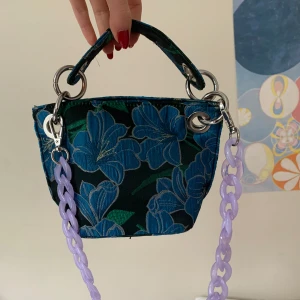 Blommig handväska med lila kedja från Hvisk - Miniväska från Hvisk🧚i använt men bra skick!
