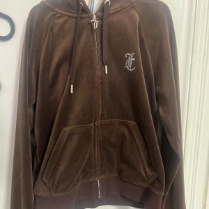 Brun velourjacka från Juicy Couture - Säljer en supermjuk brun velourjacka från Juicy Couture. Den har en dragkedja med ett  'J'-hänge och en glittrig Juicy-logga på ryggen. Dragkedjan har dock fastnat och gått sönder lite men annars ser den o använd ut. Den är i storlek S och jag är 159 cm lång. 💗💗