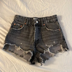 Svarta jeansshorts från Zara - Säljer ett par snygga svarta jeansshorts från Zara i storlek XS. De har en snygg slitning och fransiga kanter för en avslappnad look. Perfekta för sommardagar eller festivaler! Säljer för kommer inte till aldrig användning.