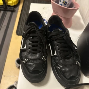 Svarta sneakers från Valentino - Säljer ett par snygga svarta sneakers från Valentino i mycket bra skick. Skorna har en cool design med vita detaljer och snörning. Perfekta för både vardag och fest! Storlek är inte angiven, men de ser ut att vara i herrstorlek. PRIS KAN DISKUTERAS 