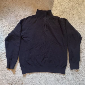 Mörkbrun stickad tröja från Dressmann - Säljer en mörkblå stickad tröja från Dressmann i storlek L. Tröjan har en halv dragkedja vid halsen och är perfekt för kyliga dagar. Den är i bra skick och passar både till vardags och lite finare tillfällen. Perfekt för höst och vinter!