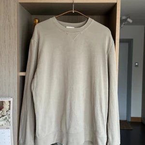 Beige tröja från COS - Storlek S - Säljer en stilren beige tröja från COS i storlek S. Den är gjord av 100% bomull och har en klassisk design med långa ärmar och rund hals. Perfekt för en avslappnad look under höst och vår. Tröjan är i bra skick och superbekväm!